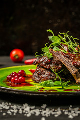 Fototapeta na wymiar Grilled pork ribs with seedlings of greens and berry sauce, top view. Copy space. The concept of American cuisine