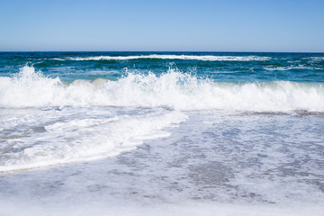 Naklejka na ściany i meble Sea waves on the beach, bright blue water