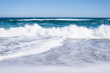 Naklejka na ściany i meble Sea waves on the beach, bright blue water