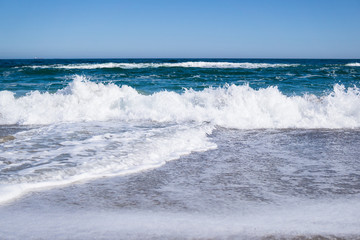 Sea waves on the beach, bright blue water