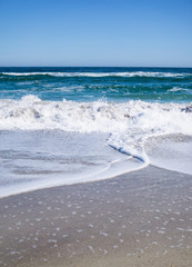 Sea waves on the beach, bright blue water