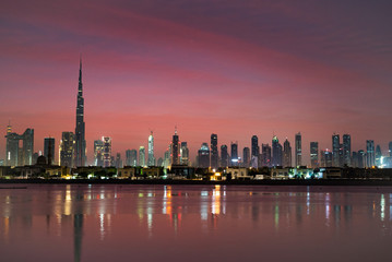 Obraz premium Dubai in night city lights or dusk. Dawn over Burj Khalifa. Nightly Dubai downtown. View from sea to Dubai quay