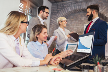 Business colleagues working on laptop in modern office.