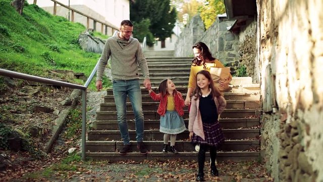 A young family with children on the stairs outdoors in town in autumn.