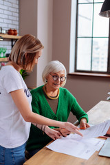 Obraz premium Beaming dame on pension considering loan application with granddaughter assistance