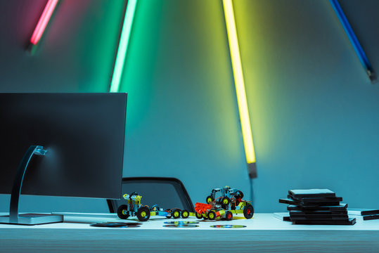 computer, toy cars and compact disks with video games on table