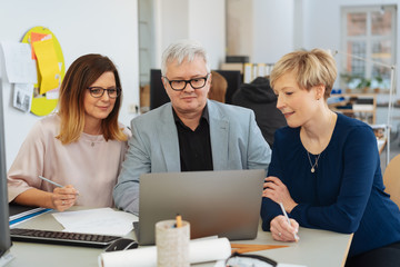 Three businesspeople gathered around a laptop