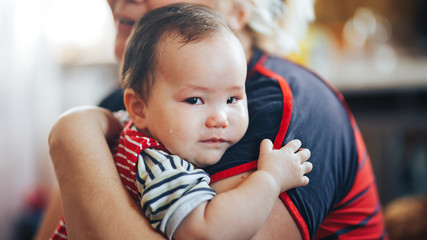 Grandmother cradling crying infant baby girl looking at camera