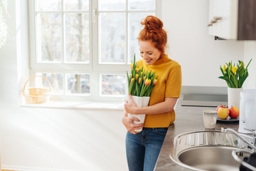 Young lady with vase of flowers in kitchen