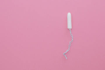 Cotton tampon on pink background. Menstrual cycle, feminine care, menstruation and intimate products concept with internal tampon isolated on pink background