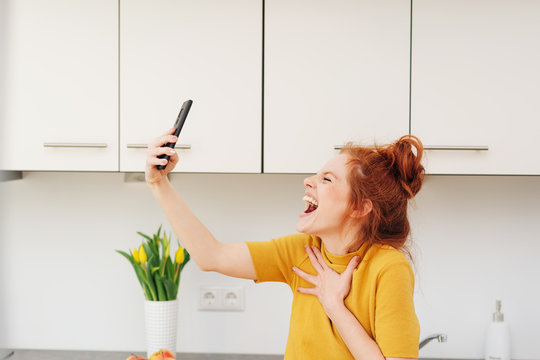 Young woman screaming or singing with smartphone