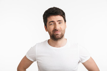 Image of unhappy man 30s with bristle in casual t-shirt frowning and grimacing