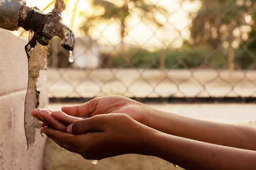 Foto op Plexiglas Closeup of hands, child drinking water directly from corporation tap water in India © WESTOCK