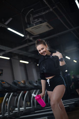Fototapeta na wymiar Fitness girl after training drank water in the gym, having fun