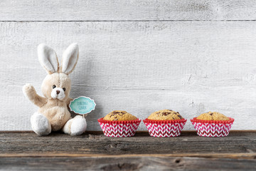Osterhase mit seinem Lieblingsgebäck vor Holzwand