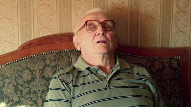 Senior man sleeping, resting on sofa at home, 4K