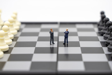 Miniature people businessmen standing on a chessboard with a chess piece on the back Negotiating in business. as background business concept and strategy concept with copy space.