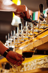 Close up of barman pouring quality dark beer into nice glass