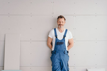 Smiling friendly handyman in denim overalls