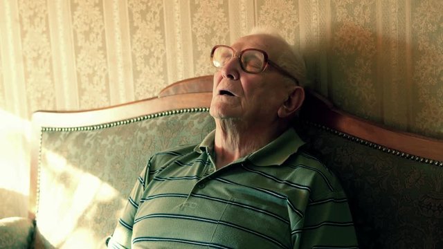 Senior man sleeping, resting on sofa at home, 4K