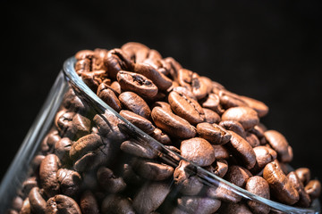 Transparent mug inside with coffee beans, all in brown tones, in a low key, close up, macro shot