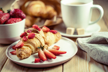 Breakfast concept with coffee cup, croissants, cream and fresh berries.