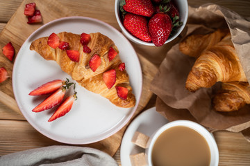 Breakfast concept with coffee cup, croissants, cream and fresh berries.