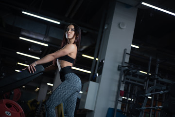 Fototapeta na wymiar Fitness girl posing in the gym, showing off her body and relaxing after a workout