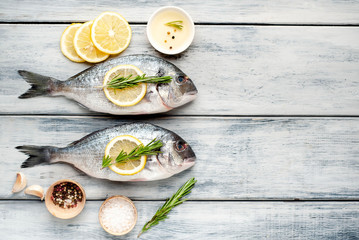 Two fresh raw Dorado fish with spices and olive oil on a wooden table.space for text 