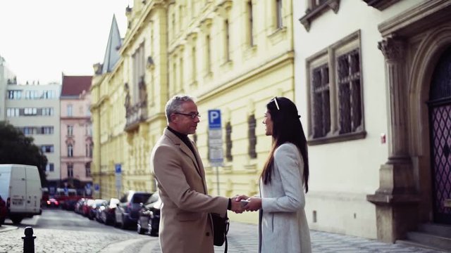 Man and woman business partners greeting outdoors in city, shaking hands.