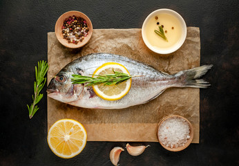  fresh raw Dorado fish with spices and olive oil on a stone background. Space for text