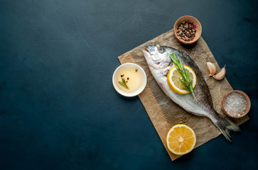  fresh raw Dorado fish with spices and olive oil on a stone background. Space for text
