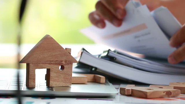 Property home model for loan real estate to buy new for family or mortgage investment concept: Wooden house models on laptop computer with businessman and chart report documents contact customer
