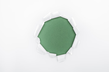 ragged hole in textured white paper on green background