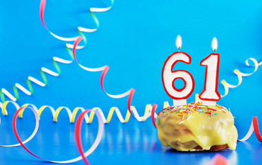 Birthday of sixty one years. Cupcake with white burning candle in the form of number 61. Vivid blue...