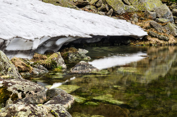 Melting snowfield and mountain lake Brebeneskul in Carpathian mountains, Ukraine