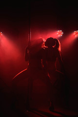 Two young girls doing acrobatic tricks with a pole