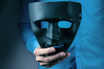 man holds mask in his hand