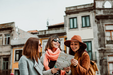 Fototapeta na wymiar .Three beautiful and funny women traveling together in Porto, Portugal. Standing together carefree and relaxed using their map to locate themselves. Lifestyle. Travel photography