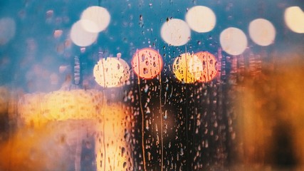 Light of evening city and rain drops on the window. Abstract blurred background. 16:9