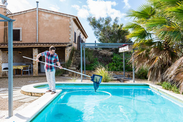 Mann genießt den sonnigen Tag an seinem Pool. Er reinigt das Wasser des Pools