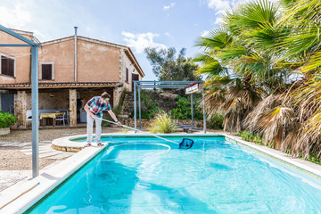 Mann genießt den sonnigen Tag an seinem Pool. Er reinigt das Wasser des Pools