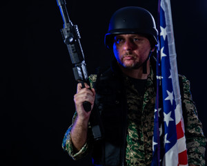 Soldier holding assault rifle and US flag