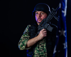 Soldier holding assault rifle and US flag