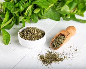 Dried peppermint in a white bowl and a bunch of fresh mint, on wooden background. Food background. © ozgur