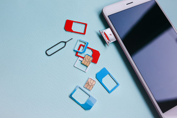 Modern smartphone lying on the table. Different micro and nano sim cards nearby. Different...