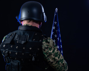 Soldier holding assault rifle and US flag