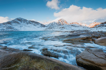Rocky coast with beautiful mountains and white clouds in the winter on the Lofoten Islands in Norway