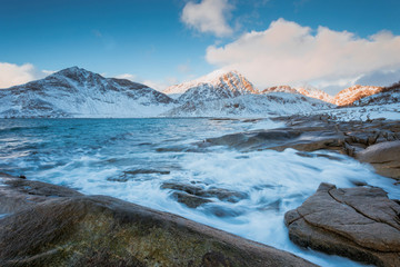 Obraz na płótnie Canvas Rocky coast with beautiful mountains and big waves in the winter on the Lofoten Islands in Norway