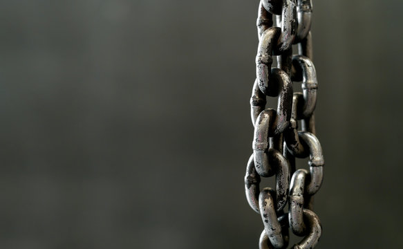 closeup metal chain on old drick wall with soft-focus and over light in the background